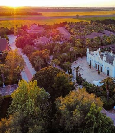 Veduta aerea di un complesso con giardini e campi al tramonto.